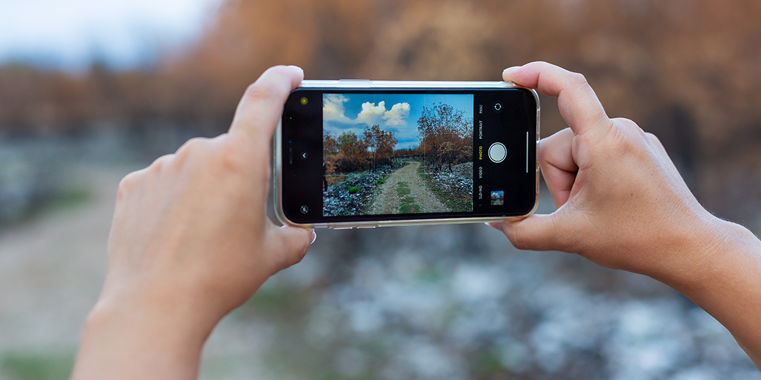first-person view of phone camera, held by two hands, taking photo of scenery